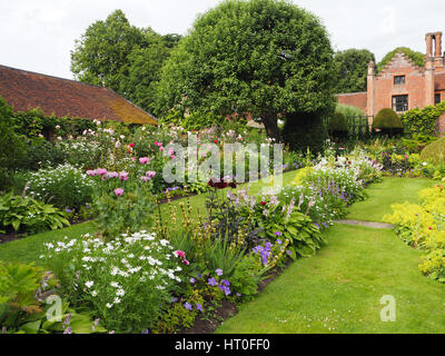 Versunkene Garten im Chenies Manor Anfang Juli. Üppige neue Wachstums- und Staudenrabatten. Mit Blick auf das Herrenhaus, alte Apfelbaum und Teestube. Stockfoto