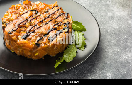 Sehr lecker die Teer-Tara sauce aus Lachs, reich an Omega 3 Öl, mit aromatischen Kräutern und Gewürzen mit einer Zitrone auf schwarzem Hintergrund. Ernährung und gesund f Stockfoto