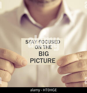 Closeup auf Geschäftsmann hielt eine Karte mit Text bleiben konzentriert ON THE BIG PICTURE, Image der Unternehmens-Konzept mit soft-Fokus-Hintergrund und Vintage-Ton Stockfoto