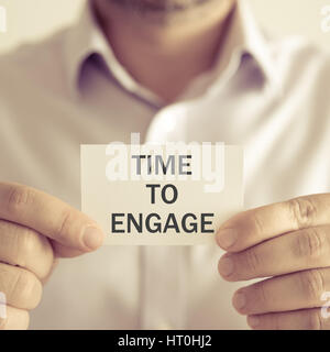 Closeup auf Geschäftsmann hält eine Karte mit Text TIME TO ENGAGE, Firmen-Konzept-Image mit soft-Fokus-Hintergrund und Vintage-Ton Stockfoto