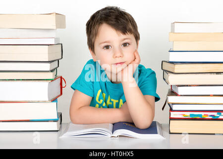 Lächelnde junge sitzt zwischen Stapel Bücher. Isoliert auf weißem Hintergrund. Stockfoto