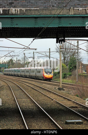 Eine Jungfrau Westküste Pendolino nähert sich Euxton Balshaw Lane-Bahnhof in der Nähe von Leyland mit Geschwindigkeit als ein Glasgow Central London Euston Train. Stockfoto