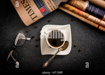 Klassen und Zeitung und Kaffee auf schwarzem Stein Stockfoto