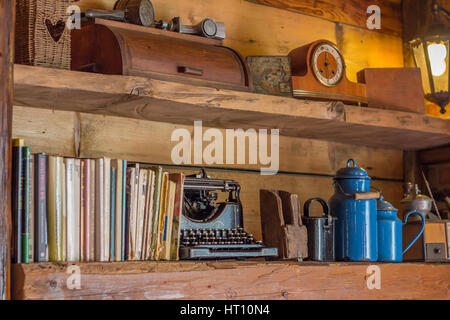 Detailansicht auf alte Holzregal mit Zeitschriften und antike Schreibmaschine Krüge Uhr und anderen Objekten Stockfoto