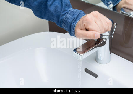 Hand des Mannes auf Wasserhahn Stockfoto