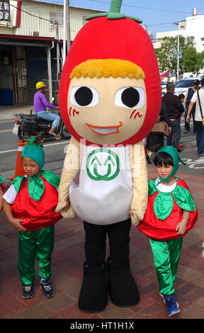 LUJHU, TAIWAN--12. Dezember 2015: eine Maskottchen verkleidet als einer Kirschtomate Posen mit zwei Kindern auf dem Lujhu-Tomate-Festival. Stockfoto