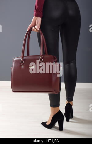 Modische Mädchen Leggings trägt und hält braune elegante Tasche Stockfoto