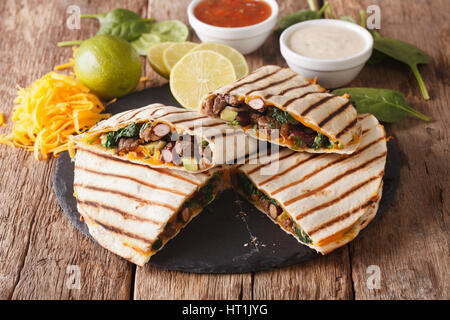 Mexikanisches Quesadilla mit Spinat, Bohnen und Cheddar Käse Nahaufnahme auf dem Tisch. horizontale Stockfoto