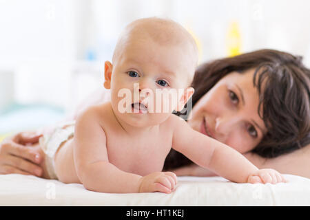 Mama und Söhnlein liegend auf dem Bett im Kinderzimmer. Mutter den Säugling Baby. Kind junge Blick in die Kamera. Stockfoto