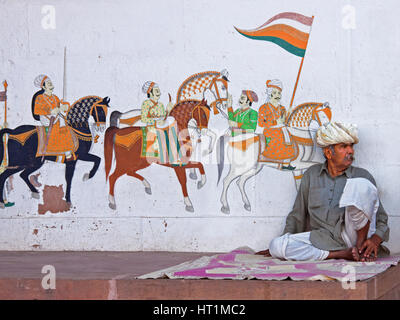 Unbekannter Mann sitzt vor Streetart in Rajasthan, Indien, mit einem typischen Gehalt an Details in der Tradition der Rajasthani-Malerei Stockfoto