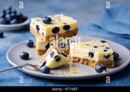 Heidelbeer-Bars, Kuchen, Käsekuchen auf einer grauen Platte auf blauem Stein Hintergrund Stockfoto