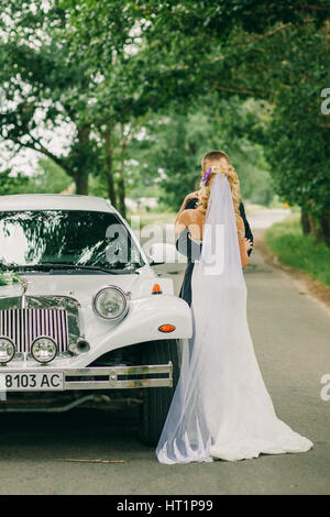 Braut und Bräutigam küssen sich in der Nähe von Limousinen. Schöne Hochzeitspaar. Stockfoto