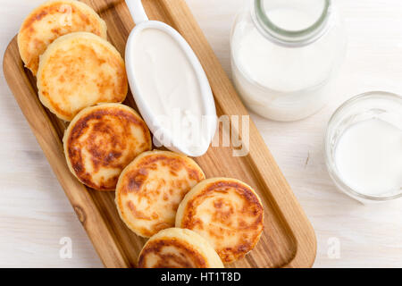 Hausgemachter Hüttenkäse Pfannkuchen auf weißen Holztisch mit saurer Sahne serviert. Syrniki, traditionelle ukrainische Küche Stockfoto
