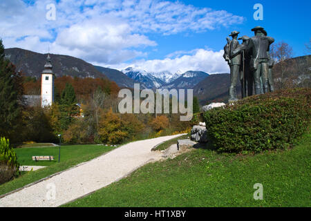Statue auf die ersten vier Männer, die den Berg Triglav besteigen neben der Kirche von St. Johannes der Täufer am See Bohinj (Bohinjsko jezero), slov gewidmet Stockfoto