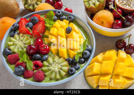 Frühstück im grünen Smoothie Schüssel mit Früchten und Beeren garniert Stockfoto