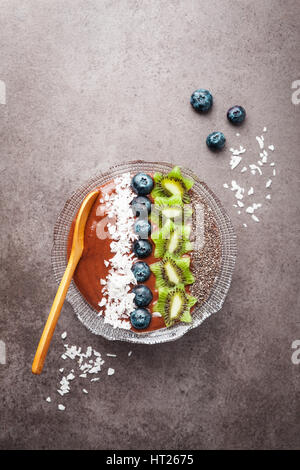 Schoko-Bananen-Smoothie Schüssel garniert mit Heidelbeeren, Kiwi, Chia-Samen, Kokos Flocken für gesundes Frühstück. Superfood Stockfoto
