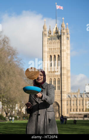 Ein Besucher dreht einen Pfannkuchen im 20. jährlichen parlamentarischen Pfannkuchen Rennen findet am Faschingsdienstag bei Victoria Tower Gardens außerhalb Houses of Parliament in London. Stockfoto