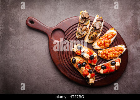 Brushetta set für Wein. Große Auswahl an kleinen Sandwiches mit Caprese Salat, weißen Bohnen auf dem Grill mit Tomatensauce und gebratene Pilze mit weichem chee Stockfoto