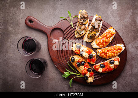 Brushetta set für Wein. Große Auswahl an kleinen Sandwiches mit Caprese Salat, weißen Bohnen auf dem Grill mit Tomatensauce und gebratene Pilze mit weichem chee Stockfoto