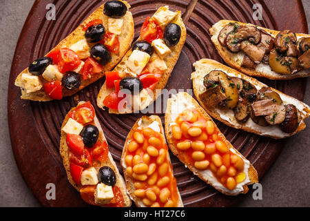 Brushetta set für Wein. Große Auswahl an kleinen Sandwiches mit Caprese Salat, weißen Bohnen auf dem Grill mit Tomatensauce und gebratene Pilze mit weichem chee Stockfoto