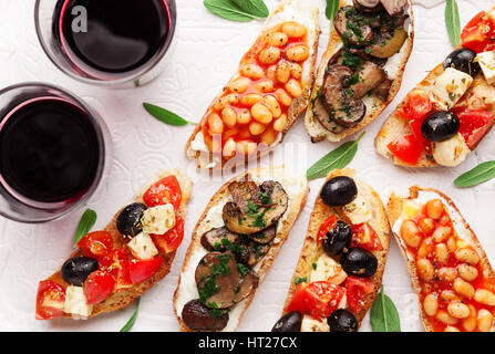 Brushetta set für Wein. Große Auswahl an kleinen Sandwiches mit Caprese Salat, weißen Bohnen auf dem Grill mit Tomatensauce und gebratene Pilze mit weichem chee Stockfoto