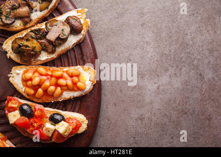 Brushetta set für Wein. Große Auswahl an kleinen Sandwiches mit Caprese Salat, weißen Bohnen auf dem Grill mit Tomatensauce und gebratene Pilze mit weichem chee Stockfoto