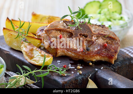 Griechisches Essen: gebratene Lammkoteletts mit gebackenen Kartoffelecken, Bauern Salat und Tzatziki Stockfoto