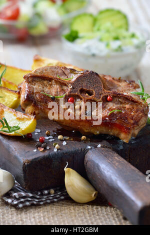 Griechisches Essen: gebratene Lammkoteletts mit gebackenen Kartoffelecken, Bauern Salat und Tzatziki Stockfoto