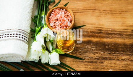 Spa-Stillleben mit Handtuch, Badesalz, Blumen und Öl auf Holz Hintergrund Stockfoto