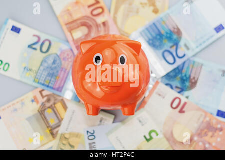 Piggy Bank beobachten einen Stapel von Euro-Banknoten und Münzen. Stockfoto