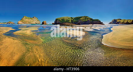 Sandstrand mit zurückgehende Wasser und felsige Insel in der Brandung, Torbogen Inseln, Wharariki Beach, Cape Farewell, Puponga Stockfoto