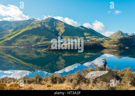 Wanderer stehen auf Felsen, Berge im Lake Moke Lake in der Nähe von Queenstown, Otago Region und Southland, Neuseeland Stockfoto