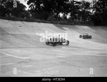 Vauxhall 30/98 und Bugatti Typ 37 Rennen auf das Banking in Brooklands. Künstler: Bill Brunell. Stockfoto