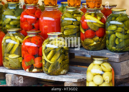 Gläser mit eingelegtem Gemüse. Gemüsekonserven. Tomaten und Gurken.  Tomaten und Gurken am Markt erhalten Stockfoto