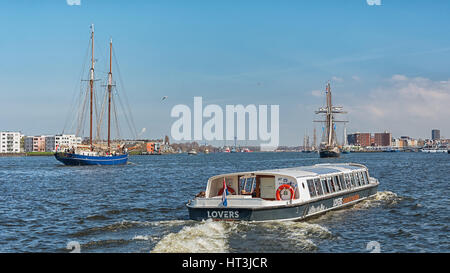 Amsterdam, Niederlande, 10. April 2016: Schiffe auf dem Fluss IJ hinter dem Hauptbahnhof von Amsterdam. Stockfoto