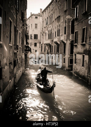 Gondoliere navigieren durch die ruhigen Kanäle Venedigs unter sanftem Nachmittagslicht und zeigen die zeitlose Eleganz der Stadt. Venedig. Italien Stockfoto
