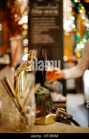 Barkeeper hinter der Theke füllt sich das Glas mit Bier vom Fass. Stockfoto