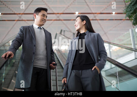 Geschäftsleute auf Rolltreppe im Flughafen Stockfoto