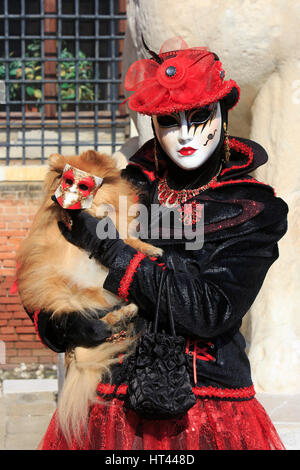 Eine Frau in Tracht Venitian hält einen Chihuahua Hund mit einer Maske vor dem Arsenal während des Karnevals in Venedig, Italien Stockfoto