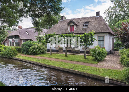 Bank stehen in den Garten um das Haus mit Blick auf den Kanal von der kleinen holländischen Stadt Giethoorn. Stockfoto