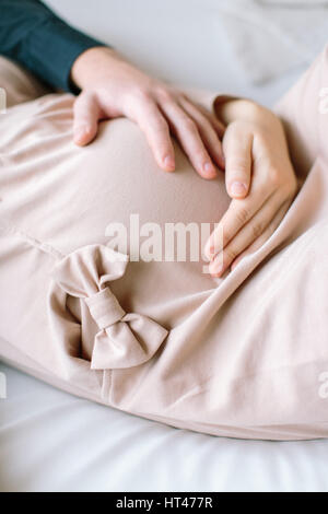 Zugeschnittenes Bild schöne schwangere Frau und ihr hübscher Mann umarmt den Bauch. Konzept der Schwangerschaft. Stockfoto