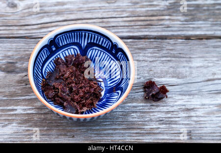 Südafrikanische Rindfleisch Biltong, Wurst in ein blau-weiß gemusterte Schüssel auf einem rustikalen Holztisch. Stockfoto