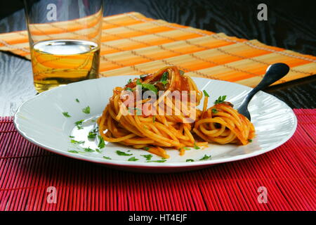Spaghetti Puttanesca mit Gabel serviert in einer weißen Schale - italienisches Rezept mit Knoblauch, Olivenöl, Sardellen, Oliven, Tomaten, Petersilie, Kapern Stockfoto