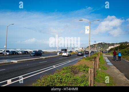 Zwei Menschen schlendern Sie in der Nähe der Great Highway am Ocean Beach in Richtung der Cliff House Restaurant (sichtbar im Abstand) im Stadtteil Endland von San Francisco, Kalifornien, 22. Januar 2017. Stockfoto