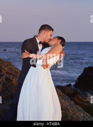 Braut und Bräutigam küssen am Strand Sonnenuntergang. Hochzeitspaar umarmen am Ozean Stockfoto