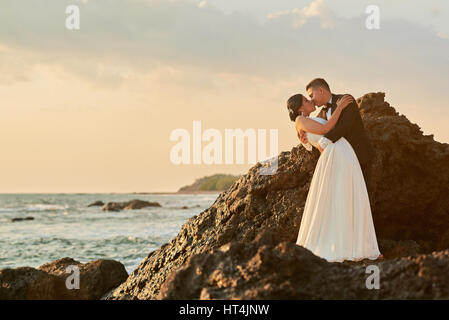 Braut und Bräutigam in Liebe küssen auf Sonne Licht Meer Sonnenuntergang Hintergrund. Hochzeit auf exotische Tropeninsel Stockfoto