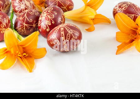 Wachs gemalte rote Ostereier und orangen Blüten Stockfoto