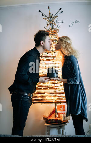 Mädchen gibt dem Mann einen Kuchen gegen eine weiße Wand Stockfoto