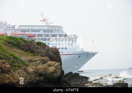 AMBER COVE Dominikanische Republik 9. Februar 2016: Carnival Ecstasy Kreuzfahrtschiff verlassen Hafen mit Felsen im Vordergrund Stockfoto