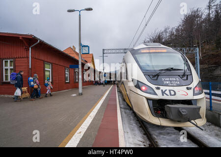 Szklarska Poreba, Polen - Februar 2017: Touristen mit Rädern Gepäck Fälle boarding bereit, Lokalbahn betriebene Koleje Dolnoslaskie abzuweichen Stockfoto